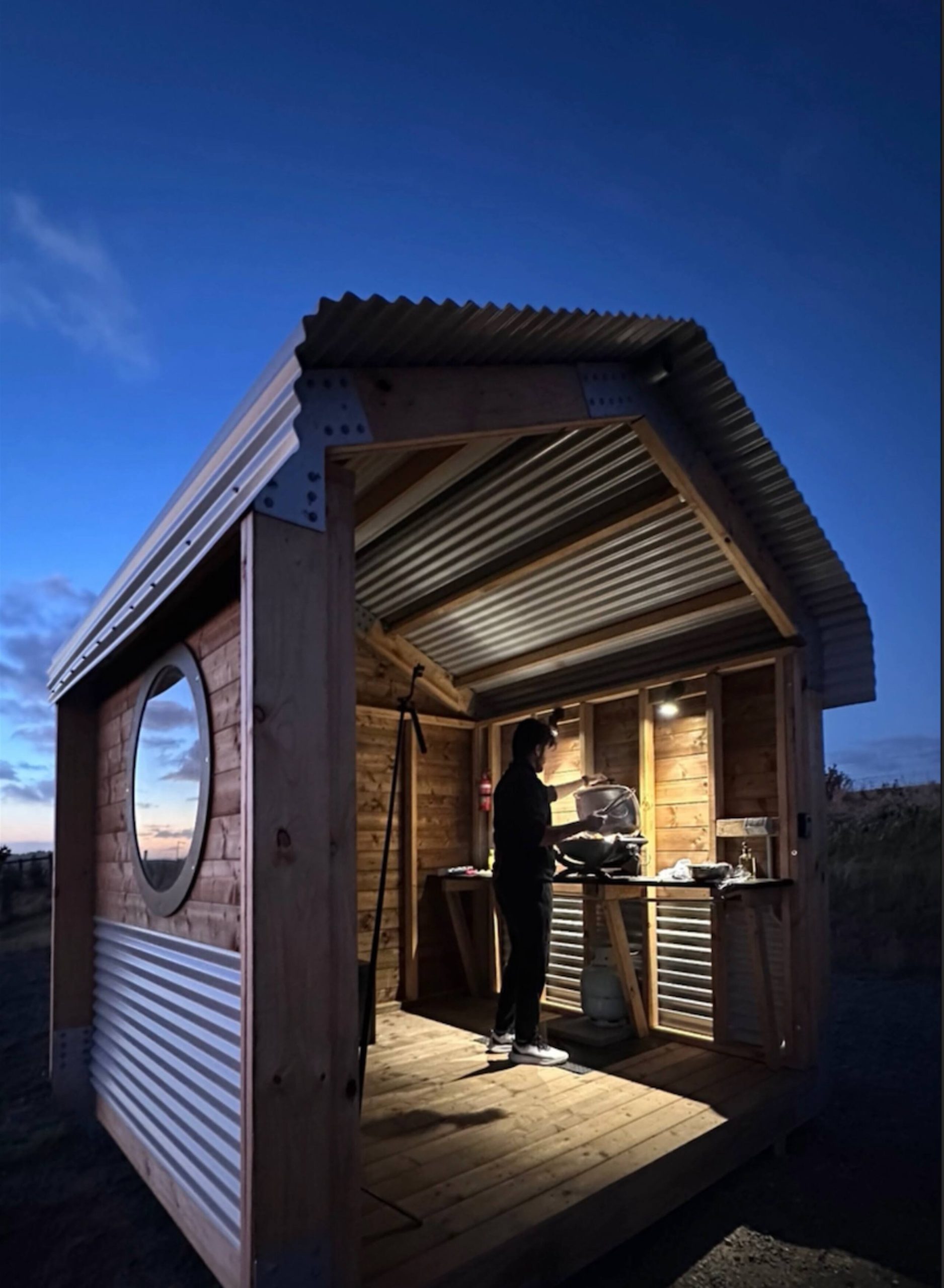 Timber BBQ hut at dusk with the Weber grill