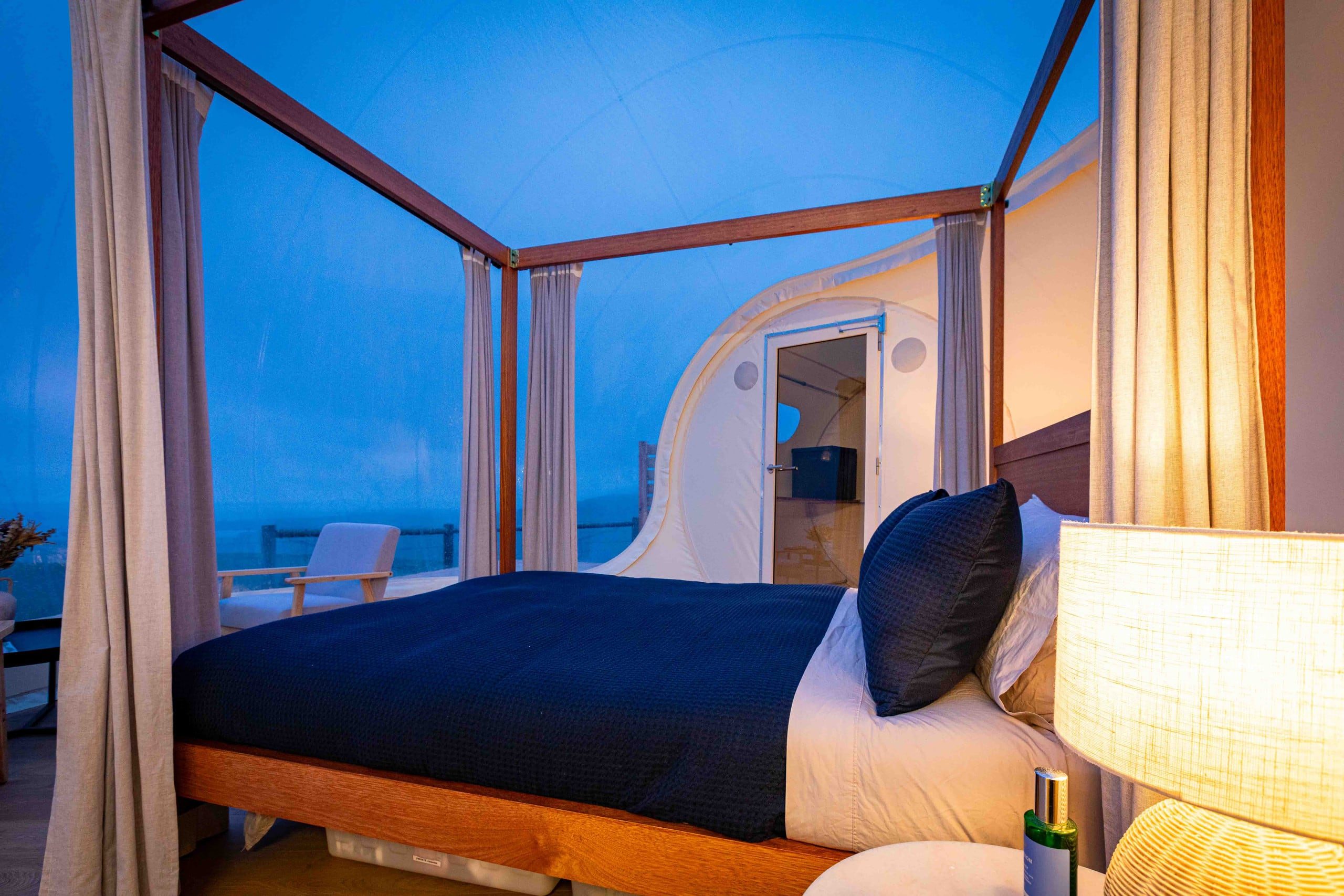 Navy four-poster bed glowing at blue hour