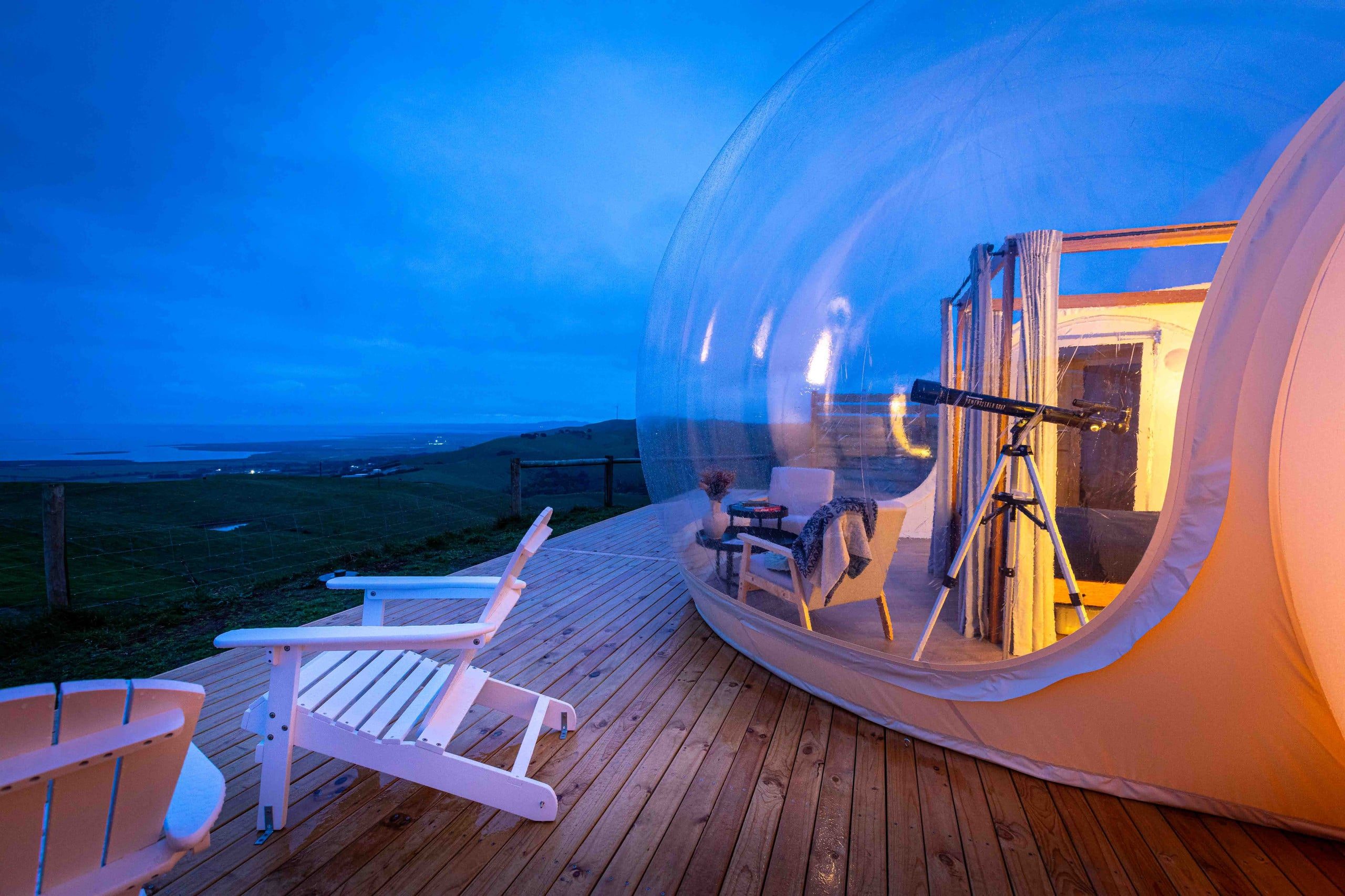Deck chairs and a telescope beside the bubble at blue hour